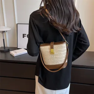 Elegante borsa a secchiello in paglia intrecciata retrò con tracolla in pelle marrone su modella