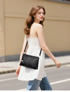 Gros plan d'un sac à bandoulière noir élégant avec motif texturé porté en extérieur.