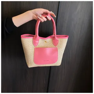 Detail close-up view of the stylish straw handbag featuring pink leather trim and pocket.
