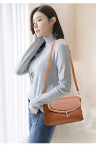 Detail view of the elegant soft leather crossbody bag with metal lock closure and strap.