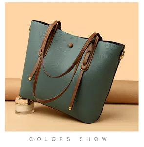 Detail view of stylish green leather tote bag with brown handles and chic metal hardware accents.