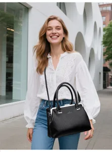 Detailed view of black leather top handle crossbody bag with metal frame clasp and shoulder strap.