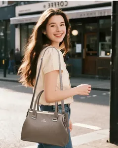 Detailed scene view of the stylish grey frame crossbody handbag worn by model on street.