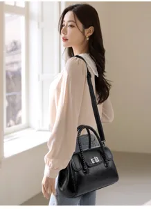 Élégant sac à bandoulière rétro noir avec poignées tressées et fermoir tournant, stylé.