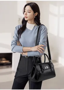 Détail de sac à bandoulière élégant en cuir noir pour femme avec fermoir vintage et poignée.