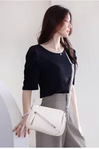 Elegant women's white leather crossbody shoulder bag worn by model, showing detail.