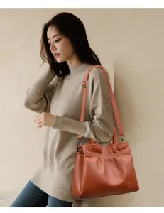 Detailed closeup view showcasing the stylish caramel leather drawstring shoulder and handbag in use.