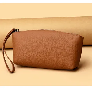 Vue détaillée de pochette poignet en cuir véritable, sac marron avec fermeture éclair et lanière.