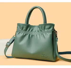 Green leather bucket shoulder bag detail, featuring soft gathered design and metal hardware.
