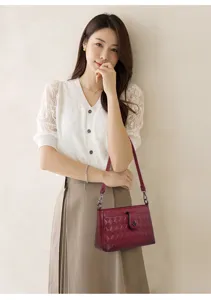 Detail shot of a wine red quilted leather shoulder bag worn by model, showcasing fine craftsmanship.