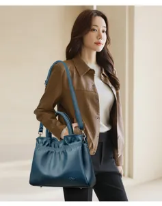 Detail view of dark blue leather bucket shoulder bag with pleated design and model show.