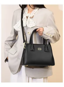 Detail view of a black leather commuter handbag, featuring golden hardware and handles.