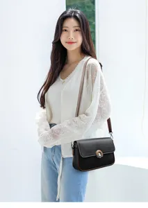 Detailed view of the stylish women black leather crossbody bag with brown strap and metal lock.