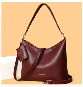 Detailed view of the dark red leather shoulder bag, highlighting its stylish pouch and hardware.