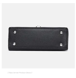 Detailed bottom view of black leather handbag featuring four protective metal feet.