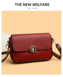 Red leather crossbody bag detail showing premium grain texture and metallic lock clasp.