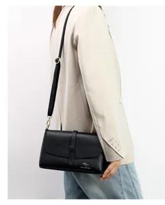Detailed shot of a stylish black leather shoulder bag with chic flap closure and gold logo.