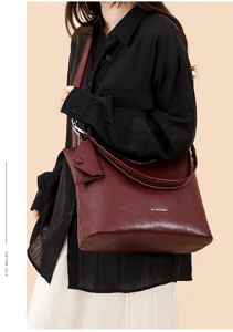Detailed shot of the large dark red leather shoulder bag with strap and cute mini pouch charm.