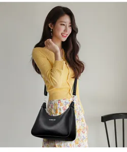 Detailed view of the black leather shoulder bag worn by model, showcasing texture and hardware.