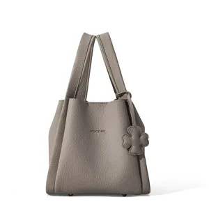 Detailed view of the stylish taupe leather bucket handbag with floral charm and handles.