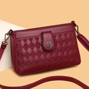 Elegant red PU leather crossbody bag with diamond quilting and chic clover clasp detail.