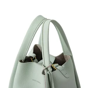 Mint green leather handbag detail showing the double handles and embossed brand logo text.