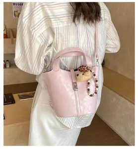 Vista dettagliata della simpatica borsa a secchiello rosa con grazioso ciondolo e manico.