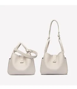 Détails du sac seau en cuir souple beige montrant les options de brides et texture.