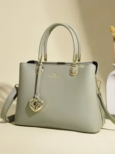 Élégant sac à main vert sauge pour femme avec anses, bandoulière et pendentif cœur.