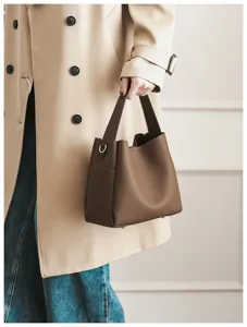 Brown pebbled leather bucket bag detail, elegant handheld design with metal hardware.