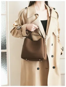 Detail view of brown soft leather bucket bag with shoulder strap and metal feet for women.