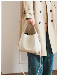 Close-up detail view of women's soft leather bucket bag with handle and crossbody strap.