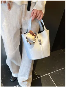 Borsa a secchiello in pelle dettaglio con ciondolo orsetto carino e chiusura, elegante.