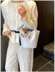 Borsa a secchiello azzurro chic con ciondolo in peluche di orsetto e chiusura in metallo.