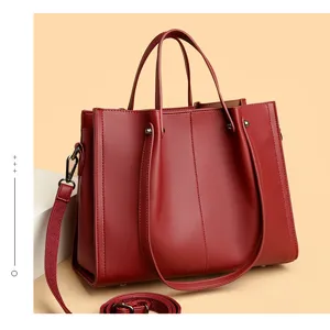 Red soft leather tote bag detail, large capacity commuter handbag with wide shoulder strap.