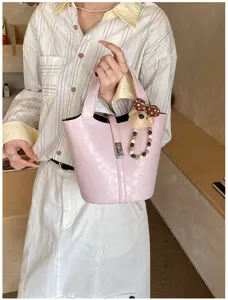 Primo piano dettagliato della borsa a secchiello in pelle rosa con lucchetto e orsetto.