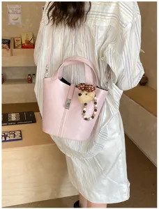 Dettaglio borsa secchiello in pelle PU rosa, grazioso ciondolo e comoda tracolla per donne.
