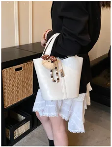 Vista dettagliata della borsa a secchiello bianca alla moda con ciondolo, stile versatile.