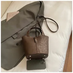 Dettaglio borsa secchiello marrone con texture in pelle PU, cinturino e base rinforzata.