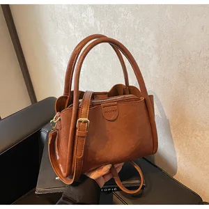 Close-up detail of brown soft PU leather handbag, showing flap closure and adjustable strap