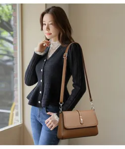 Detailed view of elegant brown leather shoulder bag worn by a model in an indoor setting.