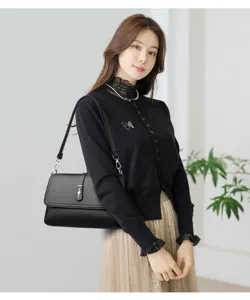 Elegant black underarm shoulder bag detail showing premium leather texture and refined metal lock.