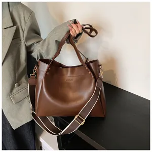 Detail view of brown leather tote bag showing fine stitching and contrast shoulder strap.