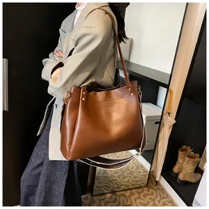 Close-up detail of brown PU leather shoulder bucket bag featuring contrast strap and hardware.