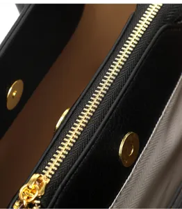 Black leather commuter tote handbag detailed view showcasing gold metal zipper and snap.