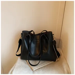 Close-up of black leather tote bag with straps, showing texture, hardware, and design details.