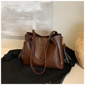 Close-up detail of the premium brown leather tote bag featuring dual straps and texture.