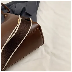 Detailed shot of women's brown leather shoulder bag with wide contrast strap fashion accessory.