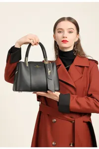 Vue rapprochée du sac à main noir en cuir texturé avec détails dorés et logo élégant.