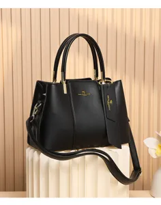 Vue détaillée du sac à main en cuir noir avec poignées doubles et accessoires dorés.